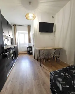 a living room with a table and a kitchen at Corte tres beau T2 neuf hyper centre 4 personnes calme et lumineux wifi lave linge in Corte