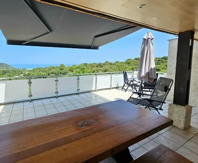 a patio with a table and chairs and an umbrella at Maison Le Guetali in Zonza