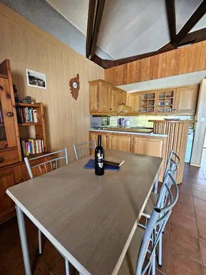 a kitchen with a table with a bottle of wine on it at Maison Le Guetali in Zonza