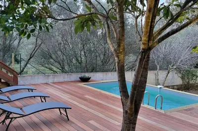 a wooden deck with a pool and two benches at Casa Marcelli 3 in Porto-Vecchio