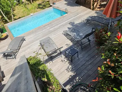 a wooden deck with chairs and a swimming pool at Casa Marcelli 3 in Porto-Vecchio