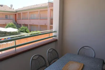 a table and chairs on a balcony with a window at Trilocale in residence con piscina a 200 m dal mare in Linguizzetta