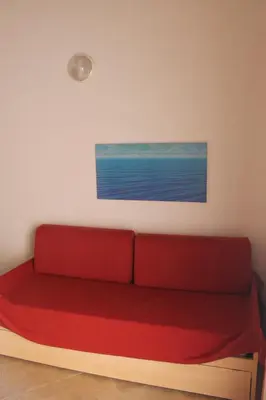 a red couch in a room with a painting on the wall at Trilocale in residence con piscina a 200 m dal mare in Linguizzetta