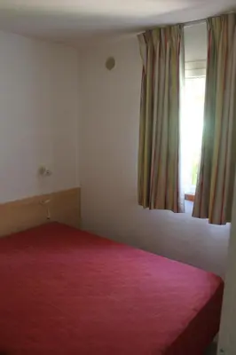 a bedroom with a red bed and a window at Trilocale in residence con piscina a 200 m dal mare in Linguizzetta