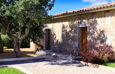 a stone building with two doors and a tree at A Liccia in Pianottoli-Caldarello