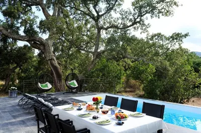 a table with food on a patio with a pool at Casa Julia in Zonza