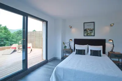 a bedroom with a large bed and a balcony at Casa Julia in Zonza