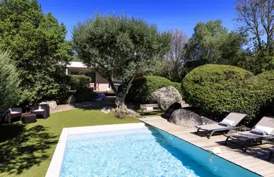 a swimming pool in a yard with trees and a house at Villa Bule in Porto-Vecchio