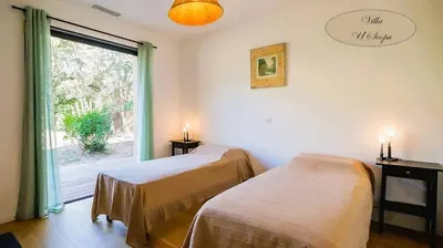 two beds in a room with a window at Villa U Scopu, 6 pers, piscine chauffée, 10 mn plage en voiture in Lecci