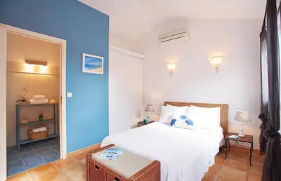 a bedroom with a white bed and a blue wall at Pinarello Beach House in Porto-Vecchio