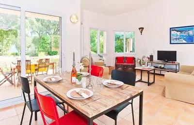 a dining room and living room with a table and chairs at Pinarello Beach House in Porto-Vecchio