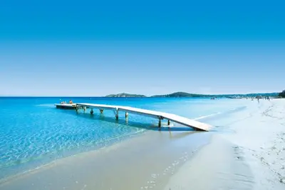 a pier in the water next to a beach at Pinarello Beach House in Porto-Vecchio