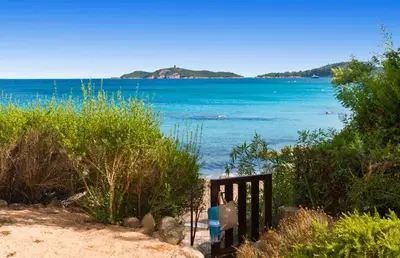 a bench on the beach with a view of the water at Pinarello Beach House in Porto-Vecchio