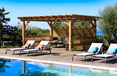 a deck with lounge chairs next to a swimming pool at The Beach House in Olmeto