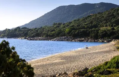 a person sitting on a beach near the water at The Beach House in Olmeto
