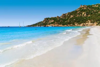 a sandy beach with the ocean and a mountain at The Beach House in Olmeto