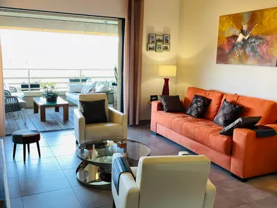 a living room with an orange couch and chairs at appartement Vue mer époustouflante in Propriano