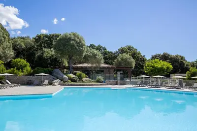 a large blue swimming pool with chairs and umbrellas at Domaine d'Arca - Aragon 12 - 4 pers in Porto-Vecchio