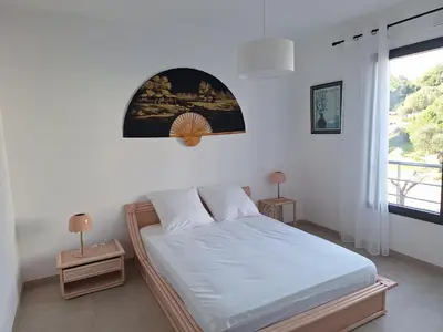 a bedroom with a bed with white sheets and a window at Domaine d'Arca - Flaubert 10 - 4 pers in Porto-Vecchio