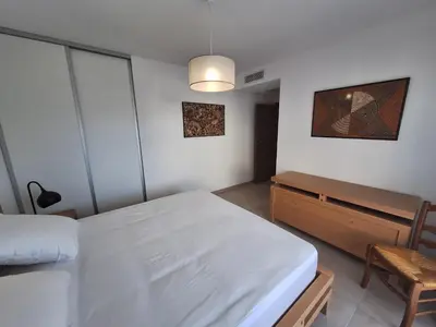 a bedroom with a white bed and a wooden dresser at Domaine d'Arca - Flaubert 10 - 4 pers in Porto-Vecchio