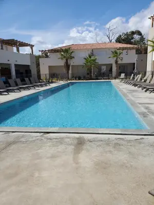 a large swimming pool with chairs and a building at Residence Marina di Bravone in Linguizzetta