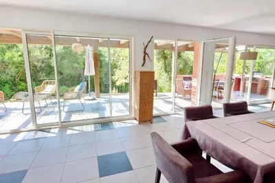 a living room with a table and chairs and a patio at Casa de Patarra Villa avec piscine privée dans un havre de paix in Peri