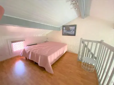 a bedroom with a pink bed and a staircase at studio mezzanine climatisé 40 M2 bord de mer in Lecci