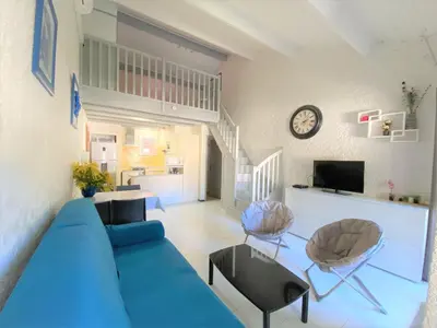 a living room with a blue couch and a clock at studio mezzanine climatisé 40 M2 bord de mer in Lecci