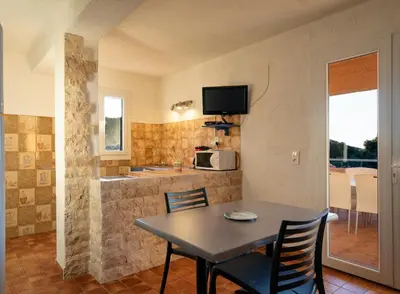 a kitchen and dining room with a table and chairs at Résidence U LATONU in Porto-Vecchio