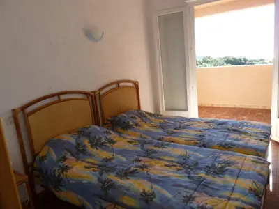 a bedroom with a bed with a blue and yellow blanket at Résidence U LATONU in Porto-Vecchio