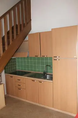 a kitchen with wooden cabinets and a sink and a staircase at Appartamento con 2 camere da letto a 200 m dalla spiaggia in Linguizzetta