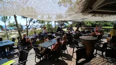 a group of people sitting at tables in a restaurant at Vignale Resort in Ghisonaccia