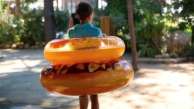 a young boy sitting on top of a fake donut at Vignale Resort in Ghisonaccia