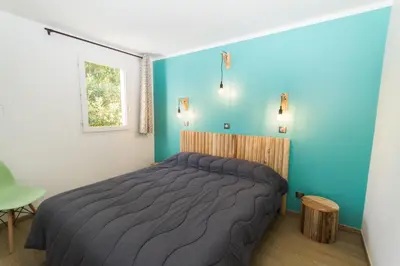 a bedroom with a bed and a blue wall at Vignale Resort in Ghisonaccia