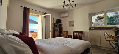 a bedroom with a bed and a kitchen with a window at T2 typique au cœur du village et vue sur le Golfe in Olmeto