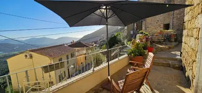 a balcony with two chairs and an umbrella at T2 typique au cœur du village et vue sur le Golfe in Olmeto