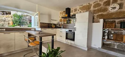 a kitchen with a table and a clock on the wall at T2 typique au cœur du village et vue sur le Golfe in Olmeto