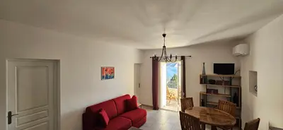 a living room with a red couch and a table at T2 typique au cœur du village et vue sur le Golfe in Olmeto