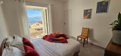 a bedroom with a bed and a large window at T2 typique au cœur du village et vue sur le Golfe in Olmeto