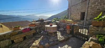 a patio with a table and chairs on a stone wall at T2 typique au cœur du village et vue sur le Golfe in Olmeto