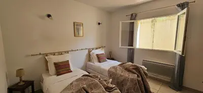 two beds in a room with a window at T3 paisible quartier Vigna Maggiore, Olmeto in Olmeto