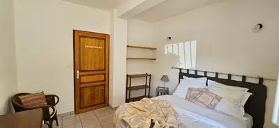 a bedroom with a bed and a wooden door at T3 paisible quartier Vigna Maggiore, Olmeto in Olmeto