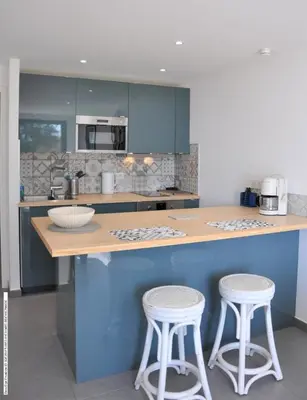 a kitchen with blue cabinets and two bar stools at Appartement RDJ ds villa vue mer panoramique in Lecci
