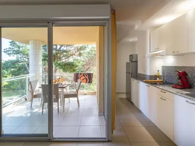 a kitchen with white cabinets and a dining room with a table at Apartment MB4 by Interhome in Moriani Plage