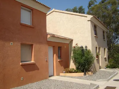 a building with a tree in front of it at Graziosa villetta in residence con piscina a 100 m dalla spiaggia in Cervione