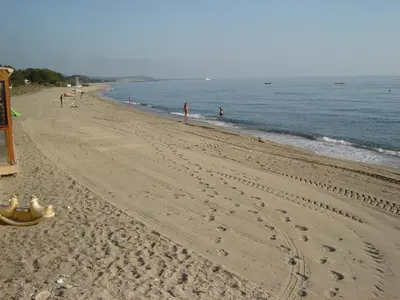 an empty beach with people walking in the water at Graziosa villetta in residence con piscina a 100 m dalla spiaggia in Cervione