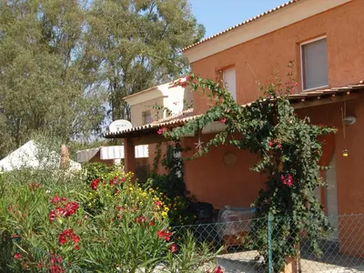 a house with flowers on the side of it at Graziosa villetta in residence con piscina a 100 m dalla spiaggia in Cervione