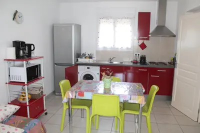 a kitchen with a table and chairs and a kitchen with red cabinets at Graziosa villetta in residence con piscina a 100 m dalla spiaggia in Cervione