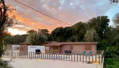 a house with a fence in front of it at Petit chalet d’été avec piscine privée chauffée in Bonifacio