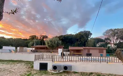 a house under construction with a sunset in the background at Petit chalet d’été avec piscine privée chauffée in Bonifacio